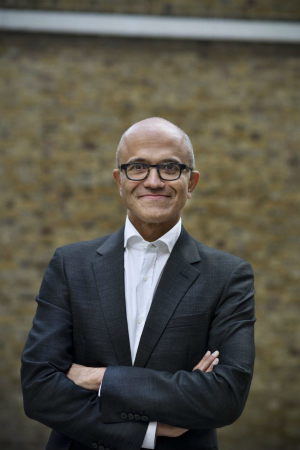 Satya Nadella stojí, usmívá se