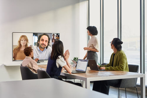 Foto, das Personen in einer virtuellen Videobesprechung in einem Konferenzraum zeigt.