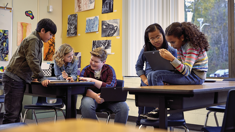 Photo of two diverse groups of students collaborating at their desks.