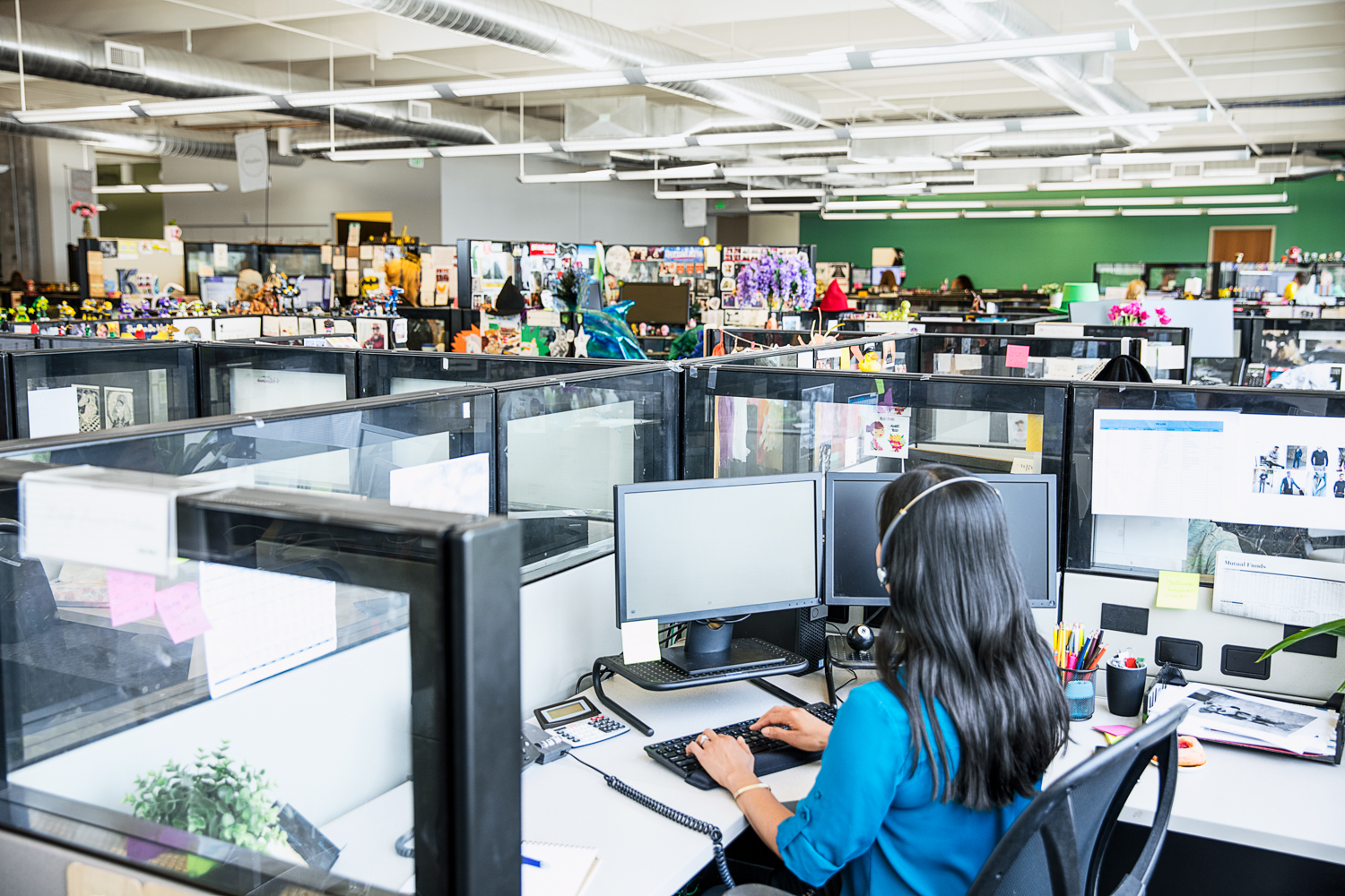 A call center worker in in a cubicle types while viewing a screen.