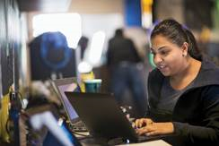 Photo of a woman sitting down and typing on a laptop computer.