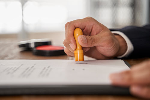 Photograph showing person stamping a paper to represent a culture of review and responsible AI.