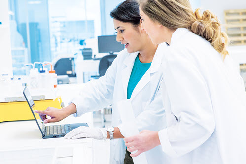 Photograph showing healthcare workers looking at a laptop.