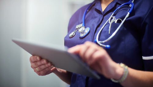 Photograph showing healthcare worker holding a tablet.