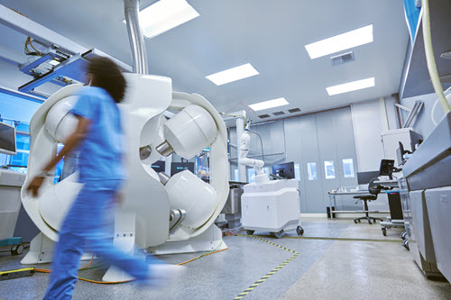 Photograph showing healthcare worker rushing through a medical room.