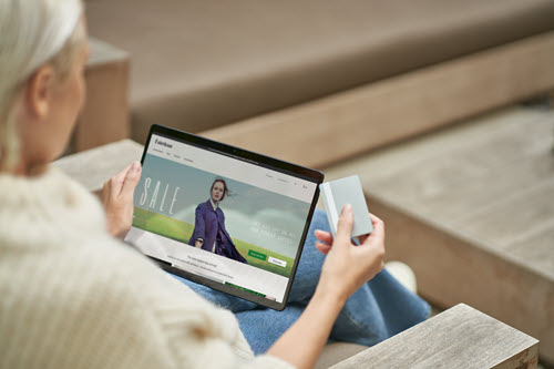 Photograph showing person shopping on a tablet holding a credit card.