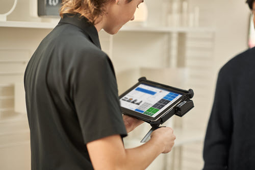 Photograph showing person standing with a tablet.