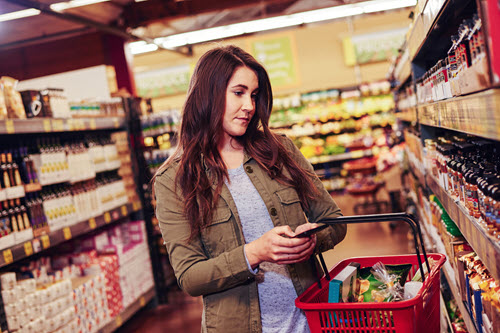 Photograph showing person on their phone while shopping in a grocery store.