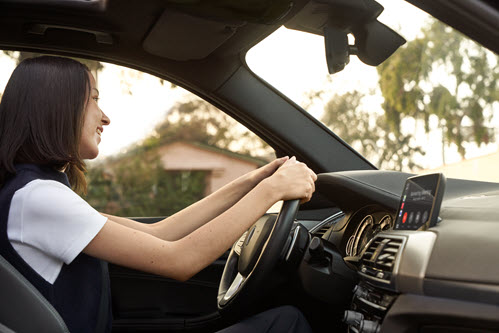 Photograph showing smiling person driving a car.