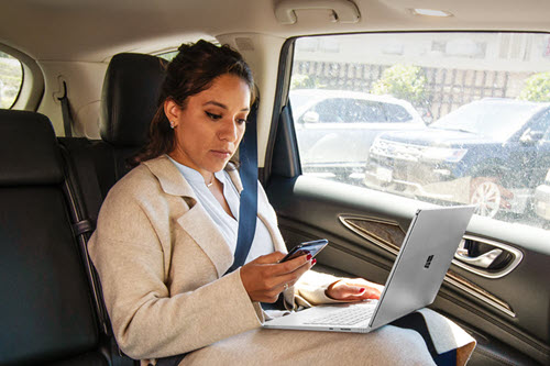 Photograph showing manager in a car using Copilot on a tablet.