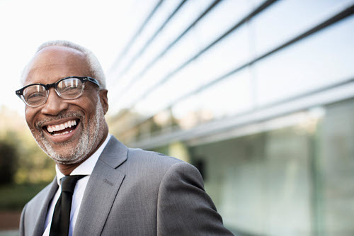 Photograph of a person who is a business leader standing in front of a building.