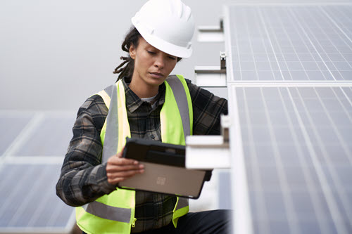 Fotografía en la que se muestra a la persona que trabaja en paneles solares con una tableta.