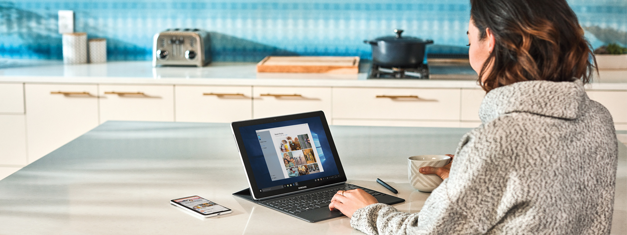 Fotografía de una mujer que usa un dispositivo Microsoft Surface en una cocina.