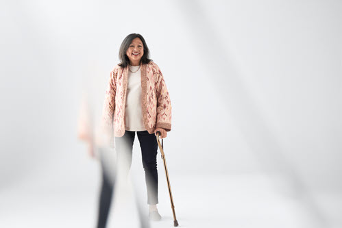 Photographie montrant une femme debout tenant une canne.