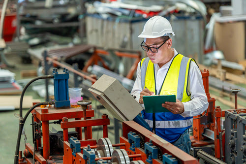 Photographie montrant un travailleur d’une usine de fabrication regardant des données.