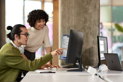 Photographie de deux personnes travaillant dans un bureau qui regardent un écran d’ordinateur.