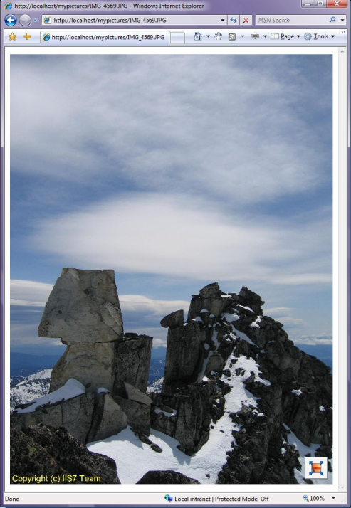 Screenshot della pagina Web che mostra un'immagine di montagne rocciose coperte di neve sullo sfondo di un cielo nuvoloso.