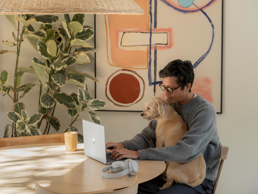 Foto van een man met een hond aan een tafel.