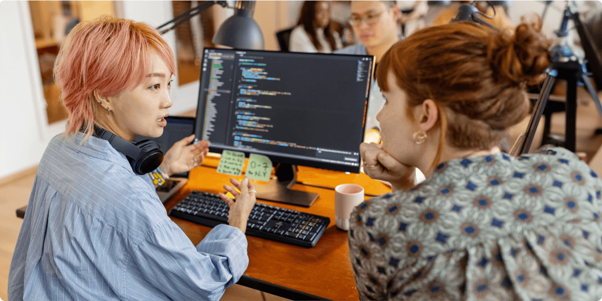 Twee vrouwen bespreken een codeervraag met elkaar, op kantoor.