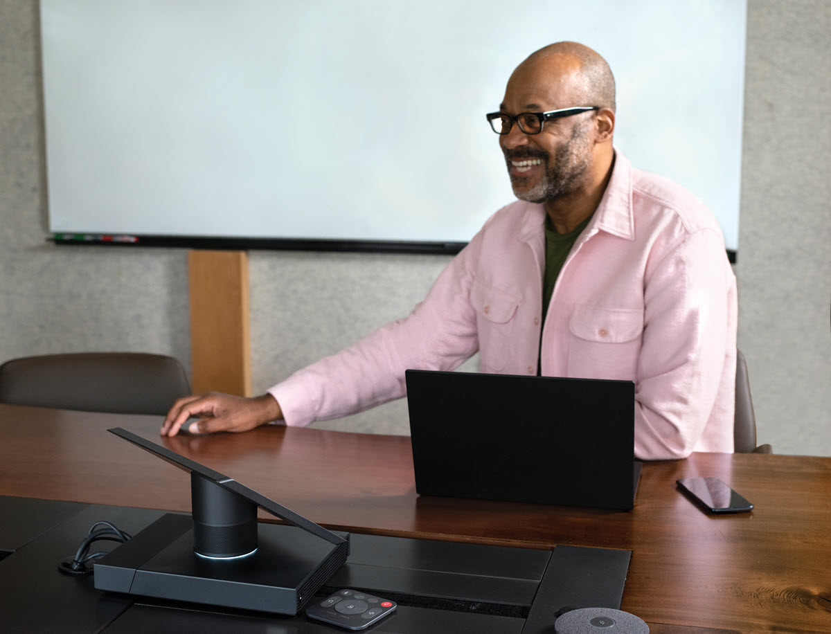 Foto de um apresentador em um notebook na frente da tela.