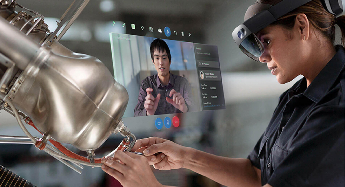 Fotografi av en HoloLens-användare som utför mekanisk reparation när han eller hon använder Fjärrhjälp för att kommunicera med en medarbetare.
